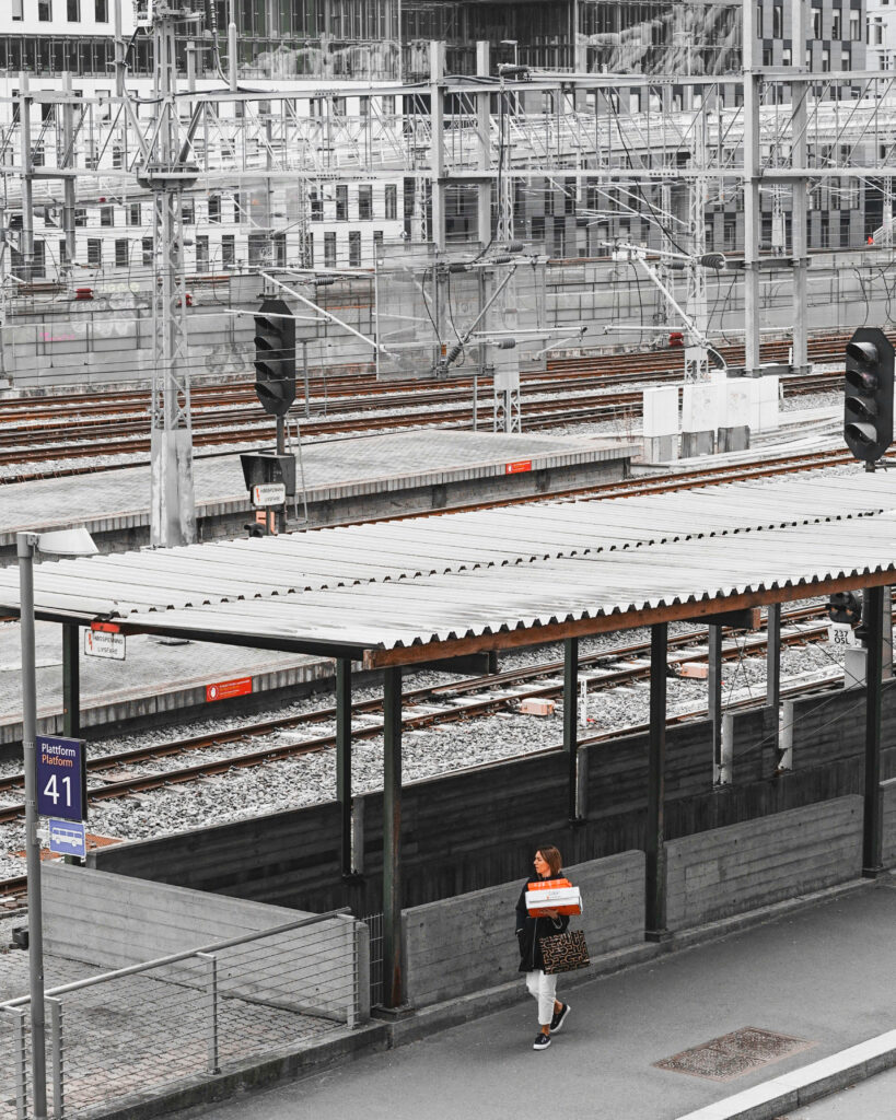 Bildet viser togskinner og elektrisk anlegg i Oslosentrum. Det er en fotgjenger på fortauet ved siden av sporene.