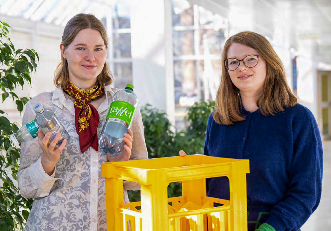 Bilde viser Nora og Solveig som smiler mot kameraet og holder plastflasker og kasser.