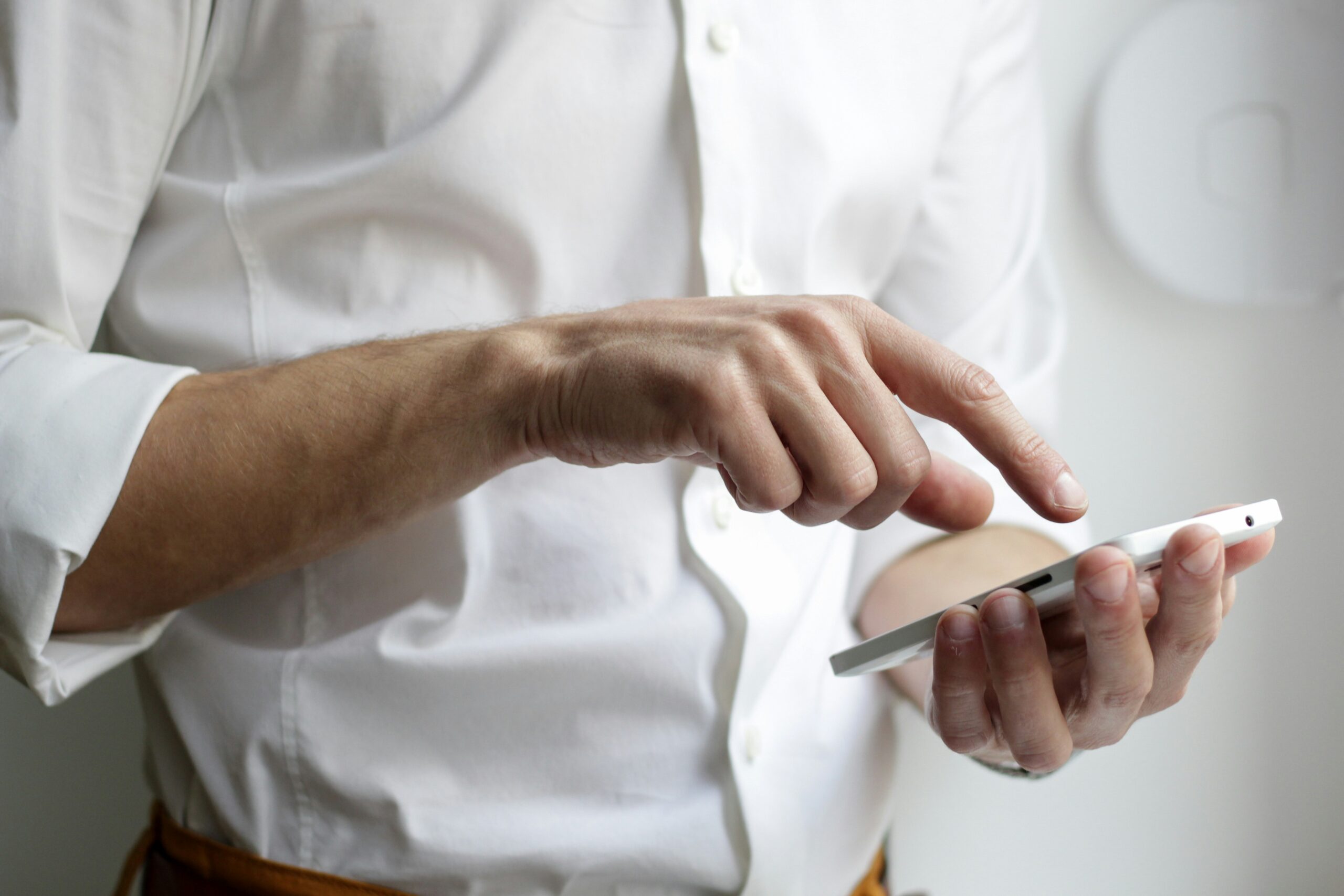 The image shows a man in a white shirt holding an Apple iPhone. Image: Unsplash