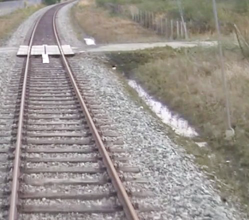 The image shpws railway tracks next to a ditch of water.