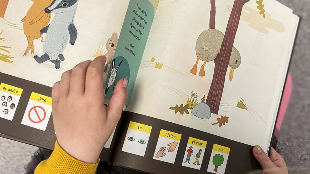 The image features the children's book "Slem" which uses graphic symbols to aid communication and language comprehension. A child's is also seen in the image.