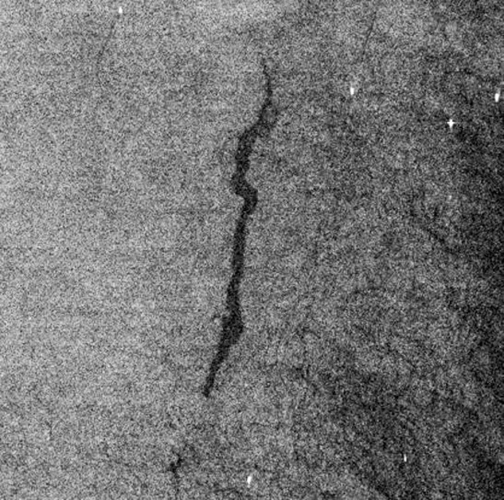 Black-and-white radar image showing oil spills as dark patches on the sea surface.
